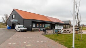A black building with a red roof, labeled 'Veerse Krek Supermarkt'. - Welcoming Family Home (Wolphaartsdijk)