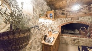A rustic kitchen with a stone wall, a wooden counter, and a brick fireplace. - Apartments Mistral - Three Bedroom Apartment With Balcony and Shared Pool (Razanac)
