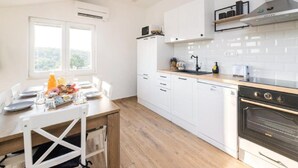 A modern kitchen with white cabinets, a wooden countertop, and a built-in oven. - Apartments Mistral - Three Bedroom Apartment With Balcony and Shared Pool (Razanac)