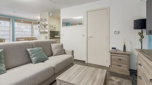 Una sala de estar moderna con un sofá, una mesa de centro y un mueble para televisión.
