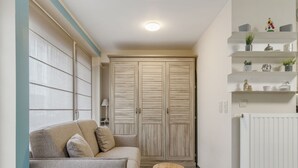Una sala de estar con un sofá, un taburete de madera, un radiador y un armario.