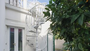 A white spiral staircase leading to a balcony, surrounded by lush greenery and a stone pathway. - Apartment Sofia by Interhome (Moneglia)