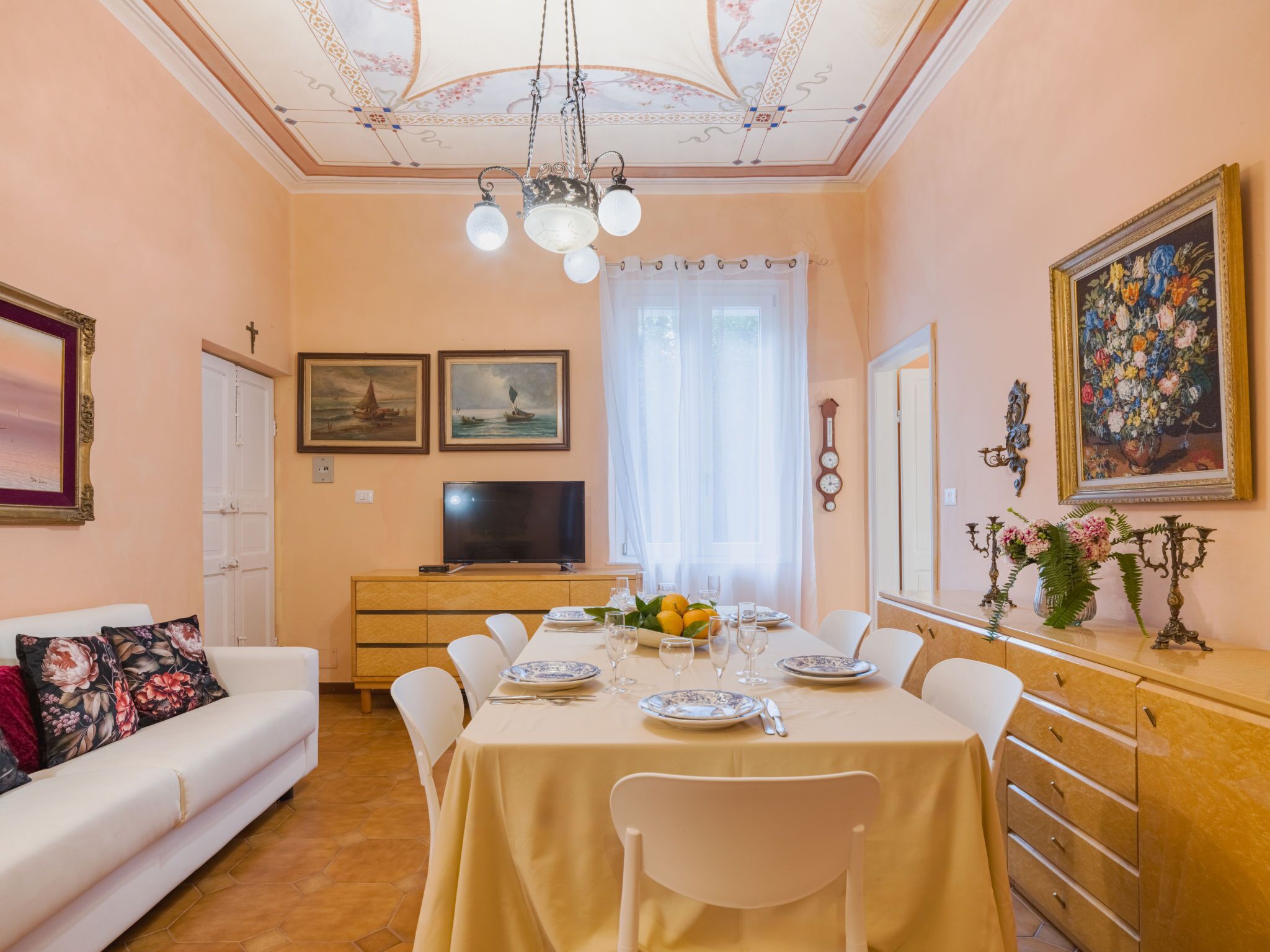 A dining area with a table set for four, a television, and artwork on the walls.