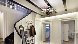 Un interior moderno con una escalera, una araña y un perchero.