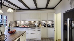 Una cocina moderna con armarios blancos, encimera de madera y salpicadero de piedra.