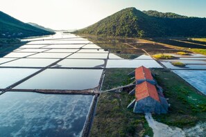 An aerial view of a large water body with a grid of floating platforms, surrounded by lush green hills.