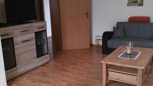 Ett vardagsrum med ett träskåp, en tv, en soffa och ett soffbord.