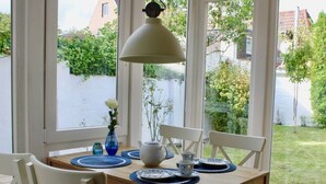 A dining table with a white lamp, blue placemats, and white chairs with blue cushions. - Holiday Apartment Stork's Nest (Friedrichstadt)