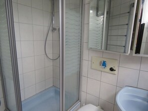 A bathroom with a shower, toilet, sink, and a mirror.