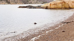 A rocky shoreline with a large boulder and a wooden dock extending into the water. - 4 Person Holiday Home in Brastad (Brastad)