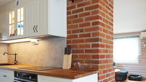 A kitchen with white cabinets, a brick wall, a wooden countertop, and a window. - 4 Person Holiday Home in Brastad (Brastad)