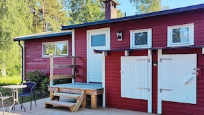 A red wooden building with a deck, two white doors, and a small window. - 4 Person Holiday Home in Brastad (Brastad)
