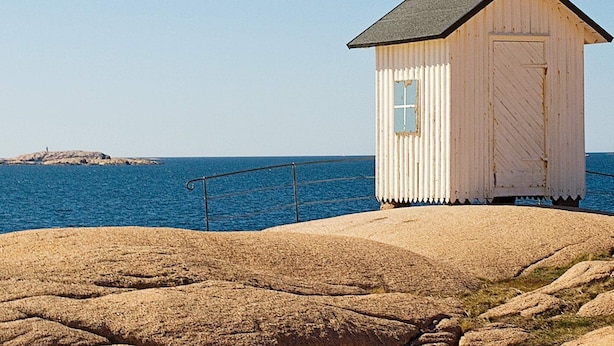 A small, single-story wooden structure with a sloped roof, situated on a rocky outcrop by the sea. - 4 Person Holiday Home in Brastad (Brastad)