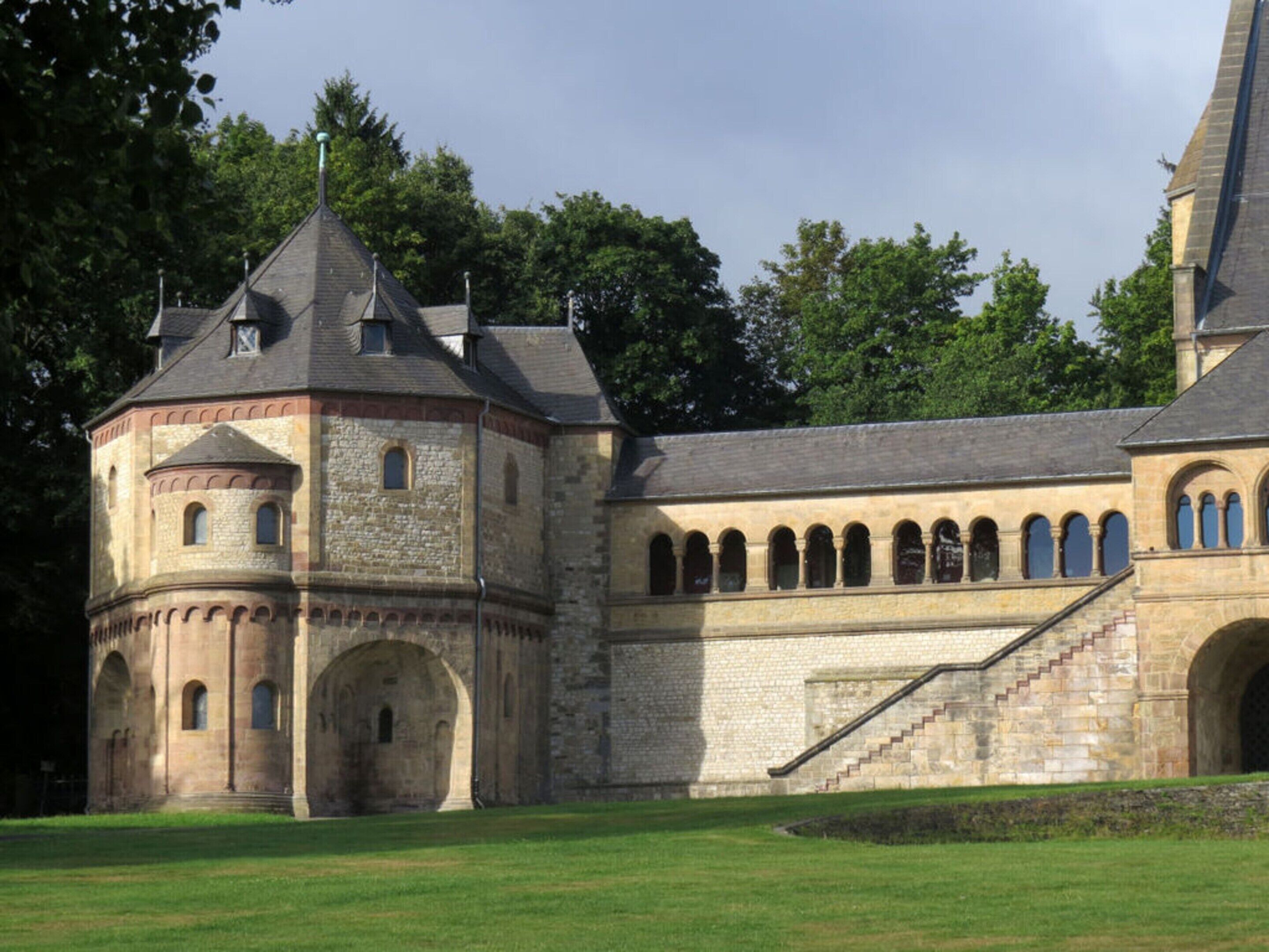 Un bâtiment historique doté d’une tourelle, de fenêtres en arc et d’un escalier menant à un étage supérieur.
