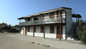 A two-story building with a balcony, a staircase, and a flagpole. - Holiday Home in Rosolina Mare Near Beach (Rosolina)