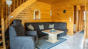 A wooden cabin interior with a staircase, a sofa, a table, and a mirror. - Holiday Home in Hasselfelde (Oberharz am Brocken)