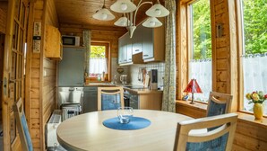 A wooden cabin interior with a kitchen, dining area, and large windows. - Holiday Home in Hasselfelde (Oberharz am Brocken)