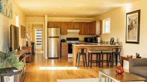 A modern kitchen with wooden cabinets, stainless steel appliances, and a bar area with stools.