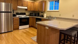 A modern kitchen with wooden cabinets, stainless steel appliances, a granite countertop, and a window providing natural light.