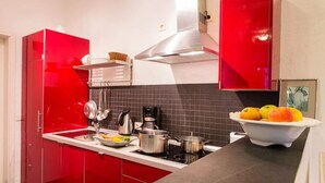 Et moderne køkken med røde skabe, en sort bordplade og en stålstålkomfur.
