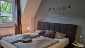 Un dormitorio moderno con una cama grande, una mesita de noche con lámpara y una pared con texto.