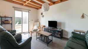A living room with a sofa, a chair, a coffee table, a TV, and a bookshelf. - Holiday Home in Koksijde With Private Garden (Koksijde)