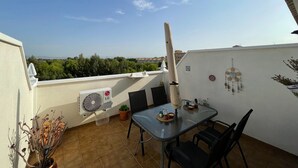 A balcony with a table and chairs, a fan, and a view of greenery and buildings. - Belvilla by OYO Casa del Segura (Formentera de Segura)
