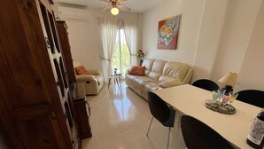 A living room with a sofa, a dining table with chairs, a ceiling fan, and a painting on the wall. - Belvilla by OYO Casa del Segura (Formentera de Segura)