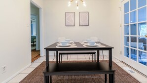 A dining area with a table set for two, a chandelier, and two framed pictures on the wall. - Modern in the Magic City (Irondale)