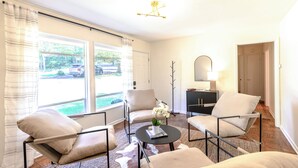 A modern living room with a sofa, chairs, a coffee table, and a lamp. - Modern in the Magic City (Irondale)