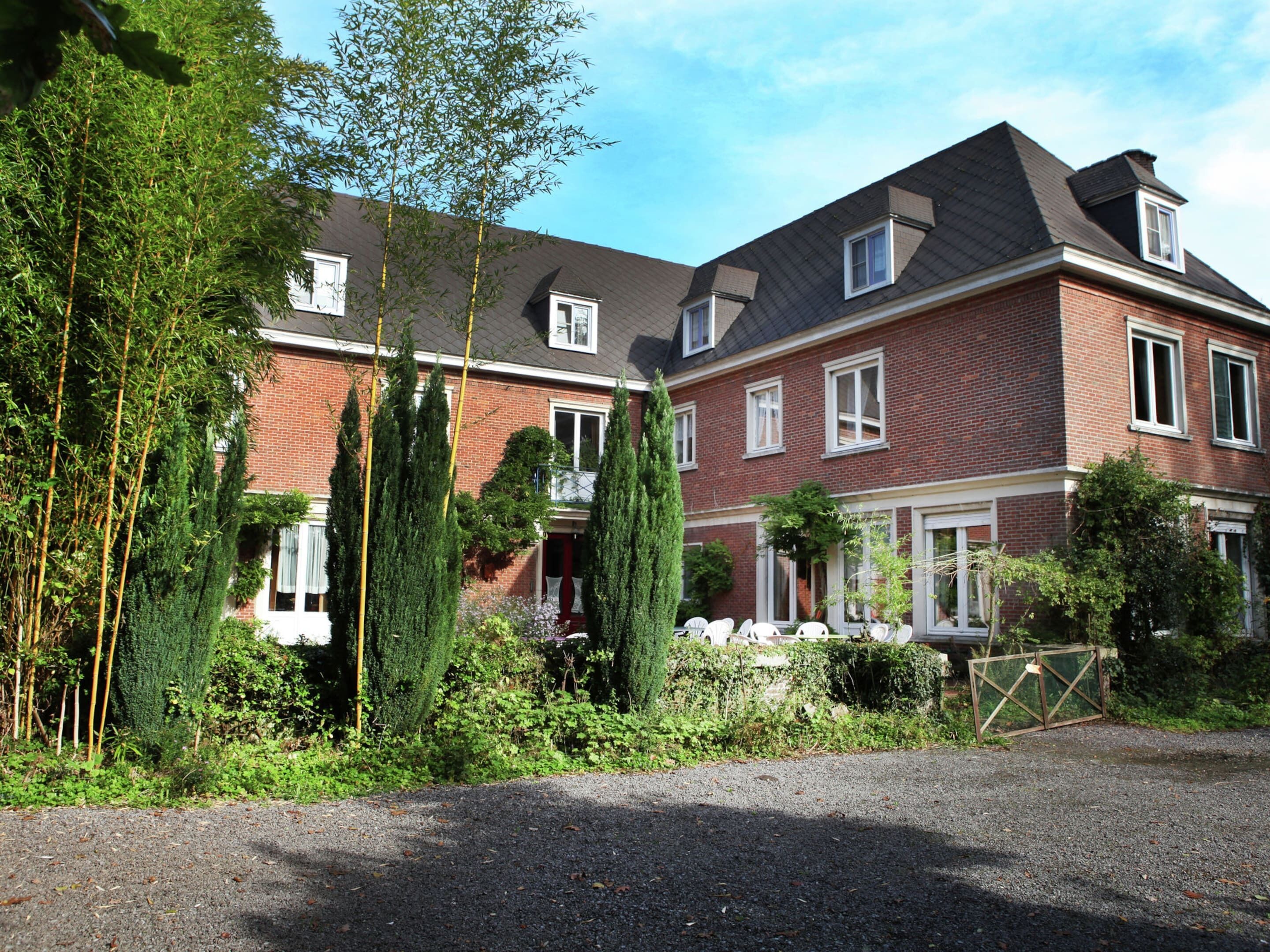 A two-story brick house with a sloped roof, a front porch, and a gated driveway.