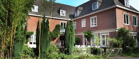 A two-story brick house with a sloped roof, a front porch, and a gated driveway.