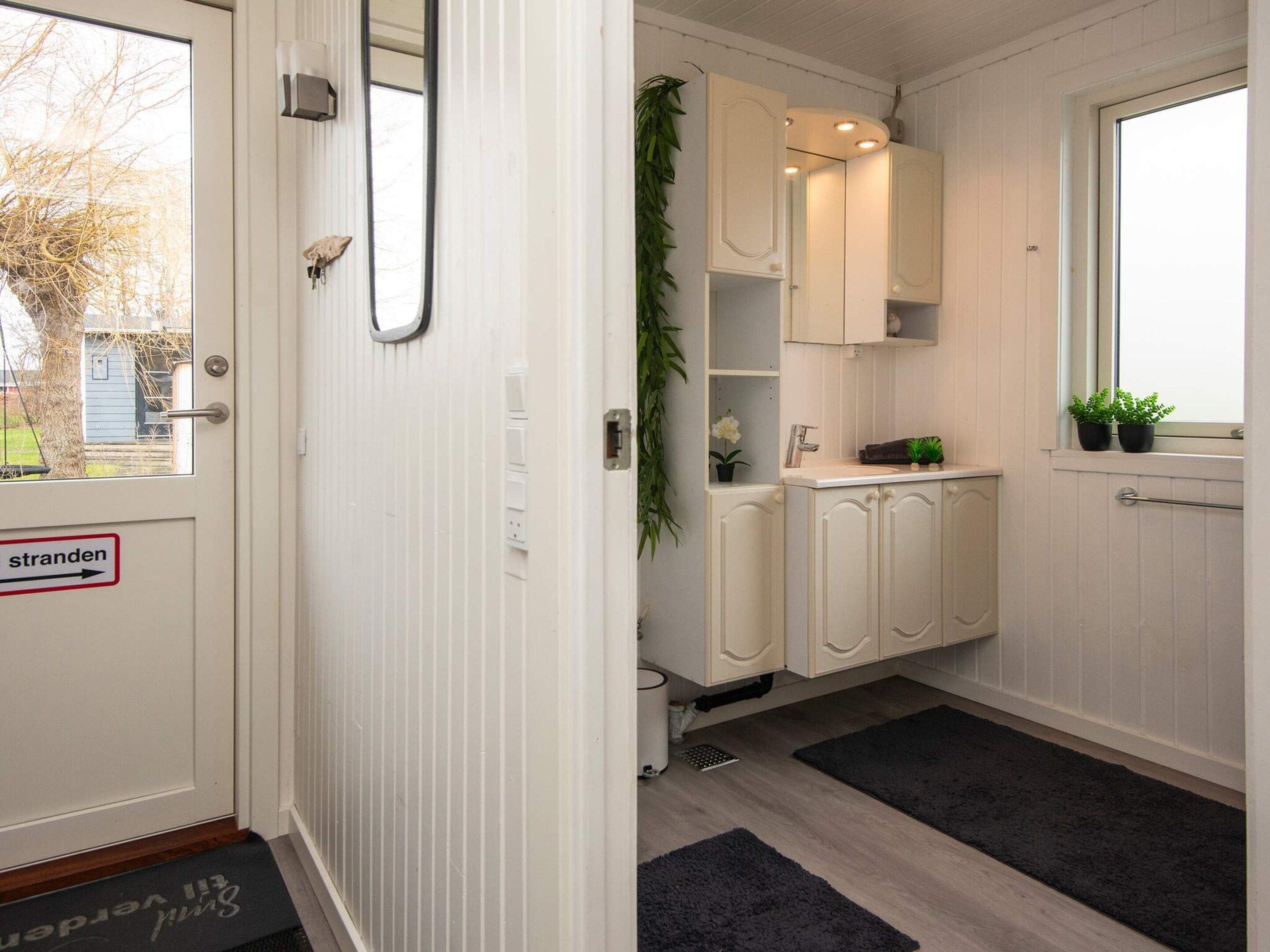 A narrow hallway with a door marked 'stranden' and a window with a view of trees.