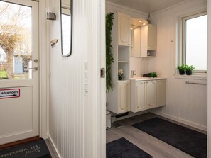 A narrow hallway with a door marked 'stranden' and a window with a view of trees.