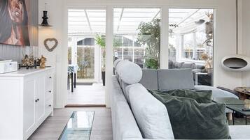 A modern living room with a sofa, a glass coffee table, and a view through a glass door to an outdoor area.