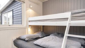 Un lit superposé avec une structure blanche, une literie grise et deux lampes de chevet.
