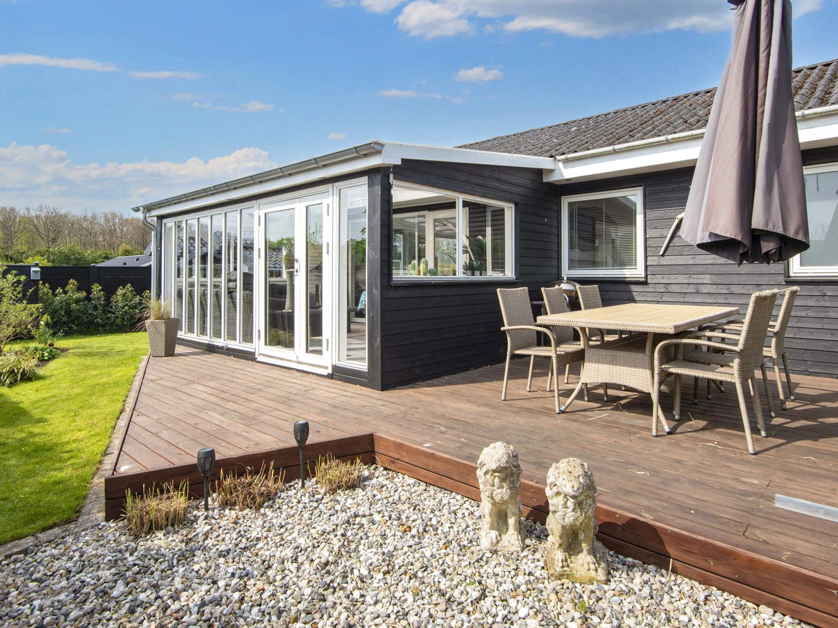A modern house with a deck, a patio table, and chairs.