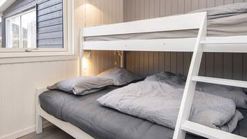 A bunk bed with a headboard, two bedside lamps, and a window with a view of the outdoors.