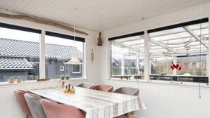 Un espace repas comprenant une table, des chaises et donnant sur l’extérieur.