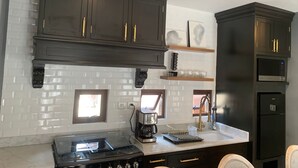 A kitchen with dark cabinets, a gas stove, a coffee maker, and a microwave. - Posada Valquiria ValQuirico (Tetlatlahuca)