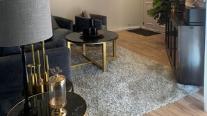 A modern living room with a sofa, a coffee table, and a lamp. There is a painting on the wall and a plant in the corner. - Posada Valquiria ValQuirico (Tetlatlahuca)