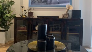 A living room with a round black marble coffee table, a large flat-screen TV mounted on the wall, a potted plant, and a bookshelf with books and decorative items. - Posada Valquiria ValQuirico (Tetlatlahuca)