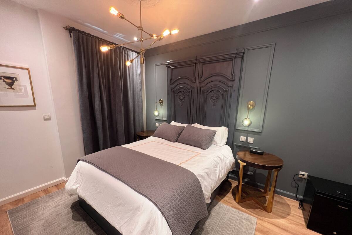 Un dormitorio moderno con una cama grande, mesitas de noche, un aparador y una lámpara en el techo.