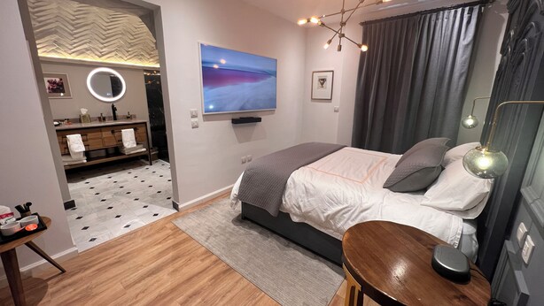 A modern bedroom with a bed, bedside table, and a TV mounted on the wall. - Posada Valquiria ValQuirico (Tetlatlahuca)