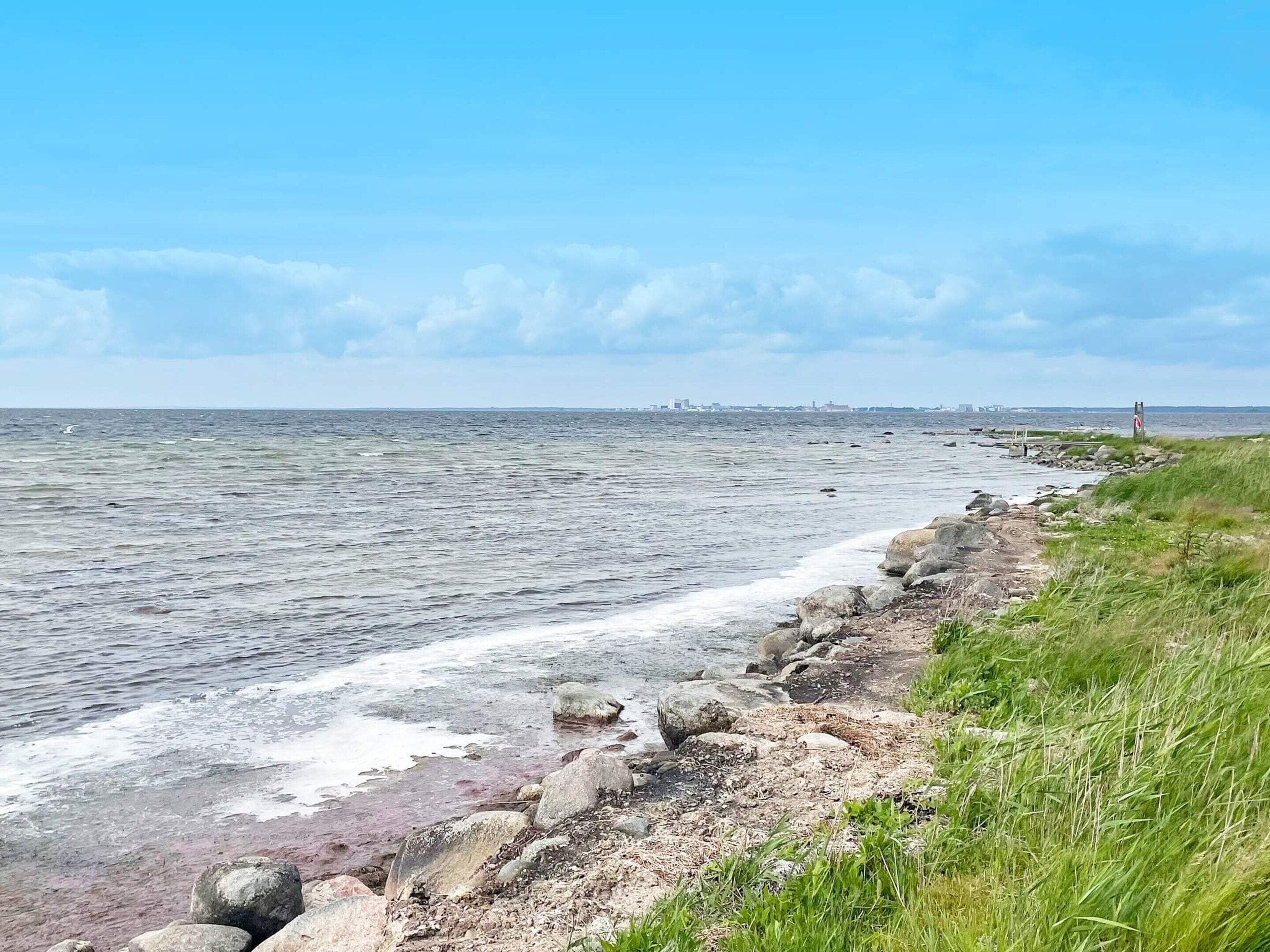 Een kustlandschap met een rotsachtige kustlijn, een grasveld en uitzicht op de zee.