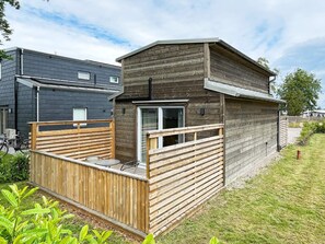 A modern wooden cabin with a deck, a window, and a door.