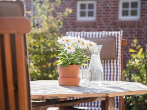 A wooden table with a terracotta pot of white flowers, a clear glass pitcher, and a striped chair. - Old Bakery - Vorderhuus (Hinte)