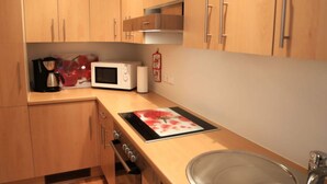 A compact kitchen with wooden cabinets, a microwave, a coffee maker, and a sink. - Apartment Pinot Noir (Lorch)
