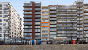 Un edificio residencial de varios pisos con balcones, una zona de estar exterior cubierta y señalización visible de las comodidades.