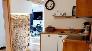 A compact kitchen with wooden cabinets, a sink, and a clock on the wall. - Apartment in Bad Hindelang-bad Oberdorf (Bad Hindelang)